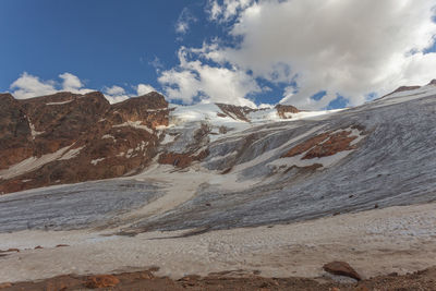 Barba d'orso glacier flowing over red mountain rocks, alto adige, italy