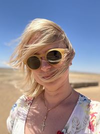 A girl in sunglasses with blonde hair blown by the wind