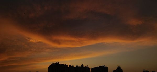 Silhouette buildings against dramatic sky