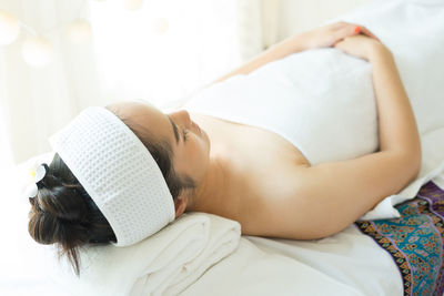 Young woman with eyes closed lying on massage table