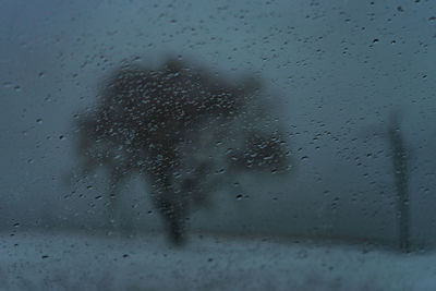 Close-up of raindrops on glass against sky