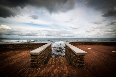 Wooden posts on beach against sky