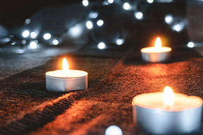 Close-up of illuminated tea light on bed