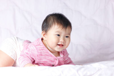 Close-up of cute baby girl lying on bed