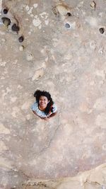 High angle portrait of smiling young woman standing on rock