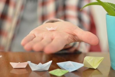 Close-up of hand holding paper painting on table