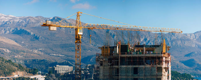 Cranes at construction site against sky