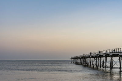 Pier over sea against clear sky during sunset