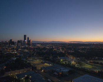 High angle view of illuminated buildings against clear sky at sunset