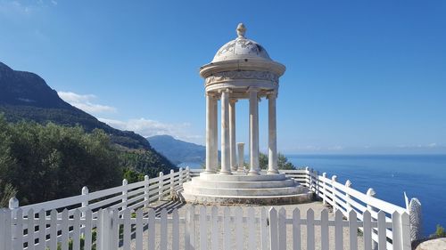 Built structure by sea against blue sky