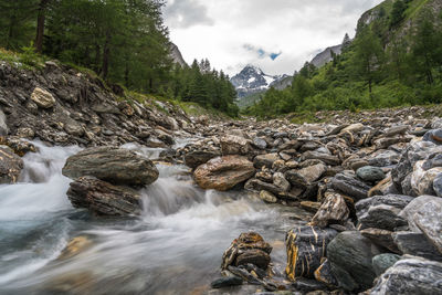 Scenic view of river flowing through rocks against sky