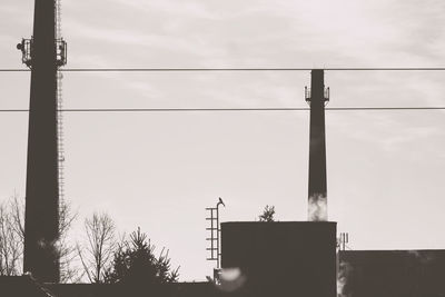 Low angle view of silhouette electricity pylon against sky