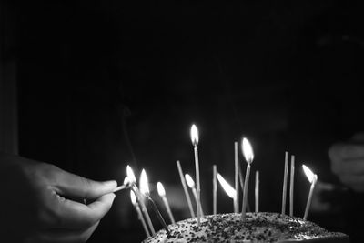 Cropped hand lighting candles on cake