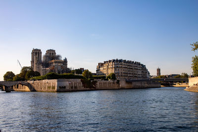 Buildings by river against clear sky