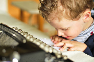 Close-up of boy with typewriter at table