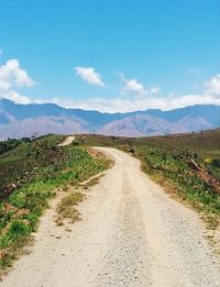 Dirt road along landscape against sky