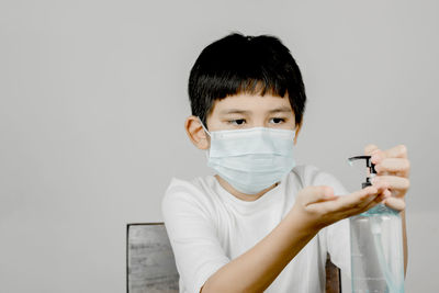 Portrait of boy holding camera over white background