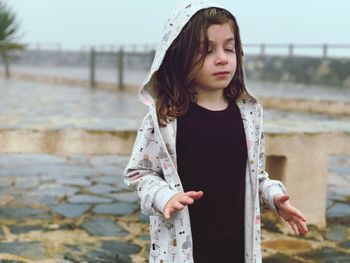 Cute girl wearing hood while standing outdoors