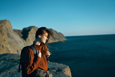 Woman looking at rock against sky