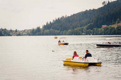 People on boat in lake against sky