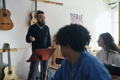 Teenagers attending guitar lesson