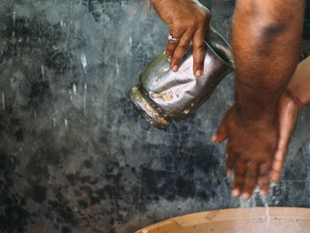 Cropped image of man pouring water on male friend hands