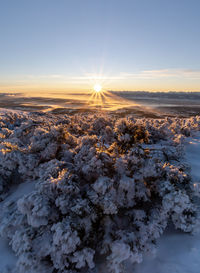 Aerial view of snow covered landscape against sky during sunset