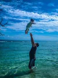 Father throwing baby daughter while standing in sea