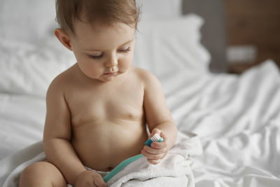 Close-up of cute baby boy sitting on bed at home