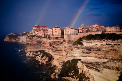 Scenic view of rainbow over rocks against blue sky