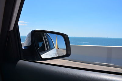 Reflection of car on sea against clear sky