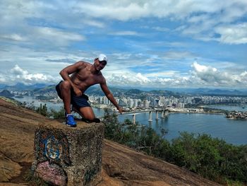 Man standing on retaining wall by sea against sky