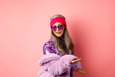 Portrait of woman standing against pink background