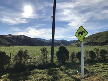 Road sign on field against sky