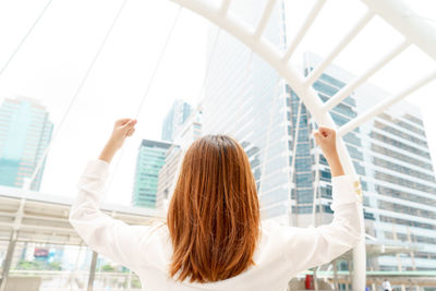 Businesswoman clenching fists against modern buildings