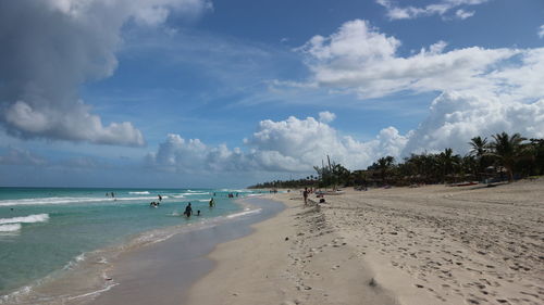 Panoramic view of people on beach against sky