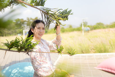 Portrait of smiling young woman against plants