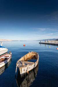 Sailboats moored in sea against blue sky