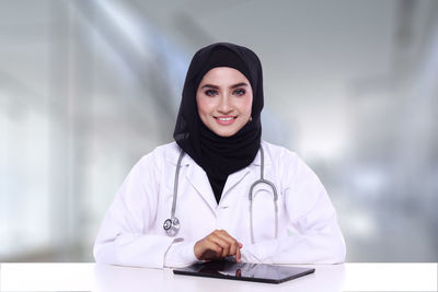 Portrait of female doctor standing against wall