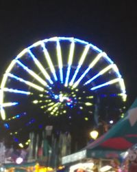 Low angle view of illuminated carousel against sky at night