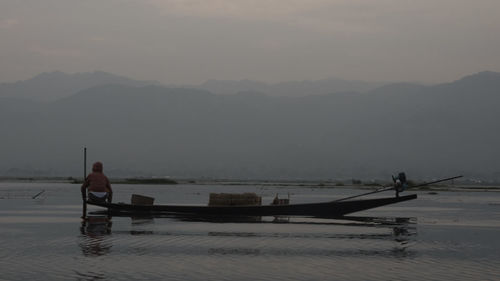 Man standing on boat in sea against sky