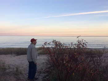 Rear view of man standing at beach during sunset