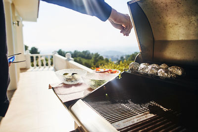 Cropped image of hand preparing food in balcony during sunny day