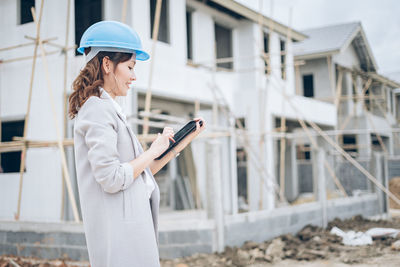 Woman wearing hat standing against built structure