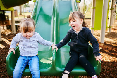 Siblings sitting on swing at park