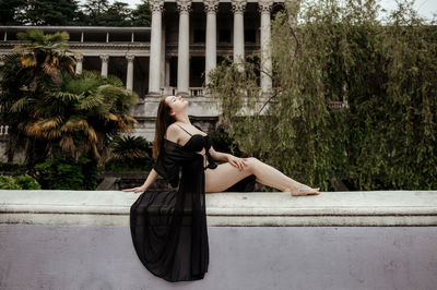 Woman standing by swimming pool against trees