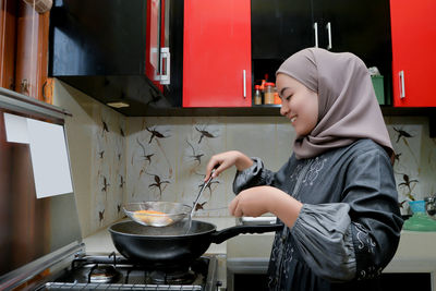 Side view of woman preparing food in kitchen