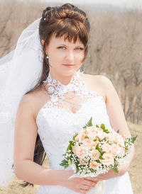 Portrait of young woman in wedding dress standing outdoors