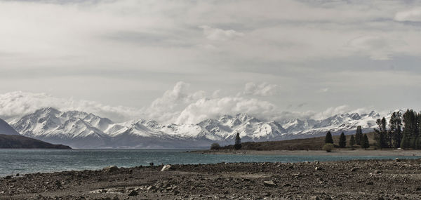 Scenic view of sea by mountains against sky