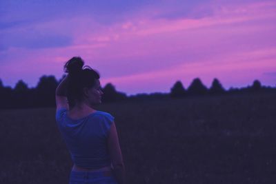 Woman standing on field against sky during sunset